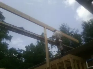 Carpenter setting a ridge beam over a new addition frame — Ice Dam Removal by Roofing Brothers in Wardensville