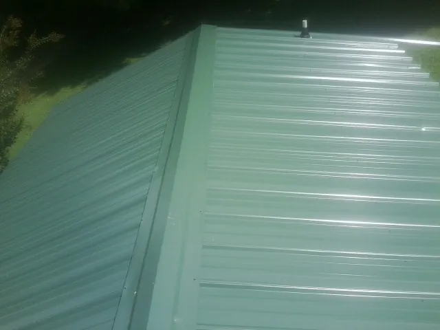 New green metal panels meeting at the ridge of a roof — Flat Roof Repair work by our crew in Wardensville