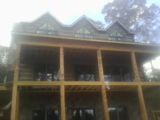 Dormers and porch framing on a large log home under construction — Roof Coating work by our crew in Wardensville