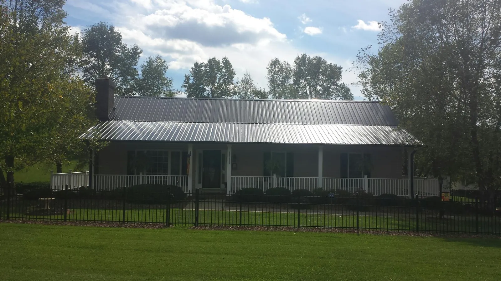 Gray metal roof on a brick ranch with a full width front porch — Gutter Guard Installation work by our crew in Wardensville