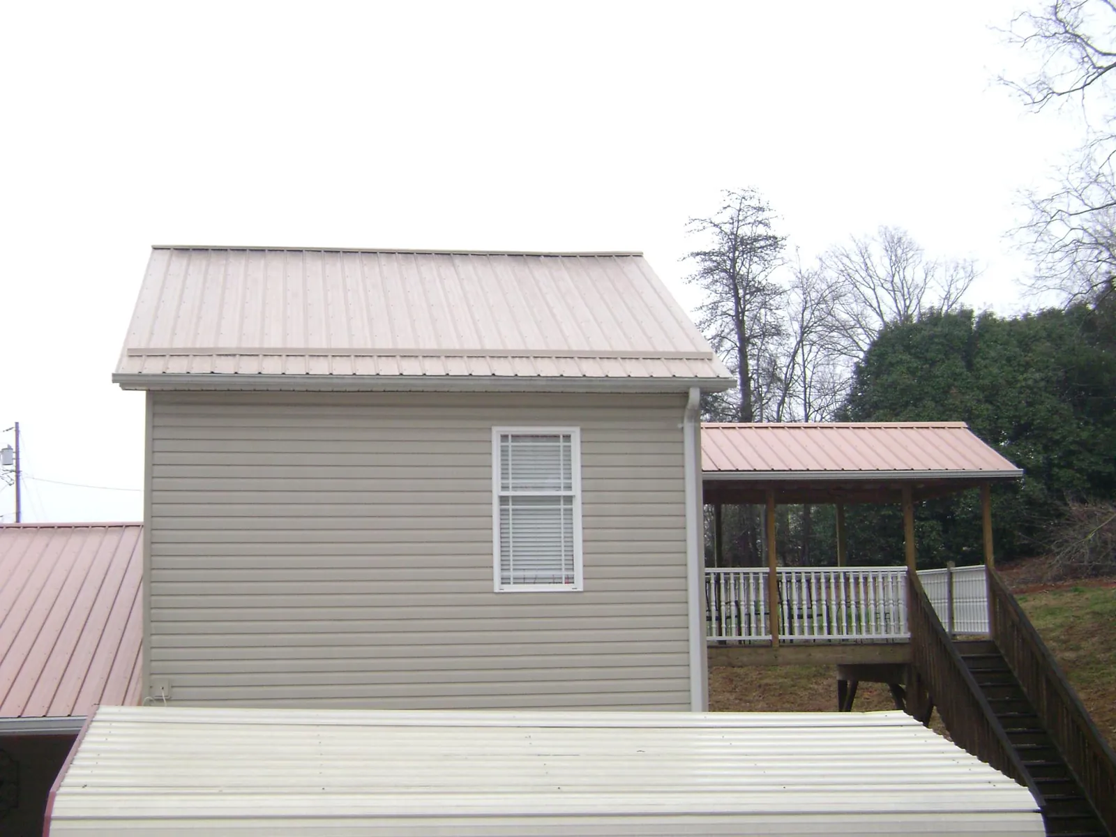 Tan metal roofs on a two story addition and attached porch, from a Roof Replacement job in Wardensville