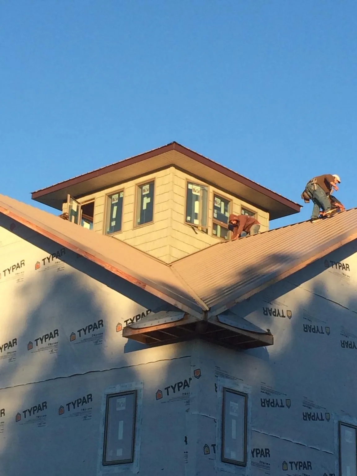 Roofers working around a rooftop cupola on a new metal roof at sunset — Roof Waterproofing in Wardensville by Roofing Brothers